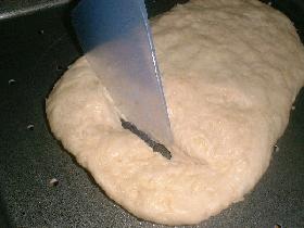 Placer sur une plaque à cuisson beurrée et faire des incisions dans la pâte (écarter la pâte pour que les incisions ne se rebouchent pas pendant la cuisson)<br /> et parsemer de gruyère